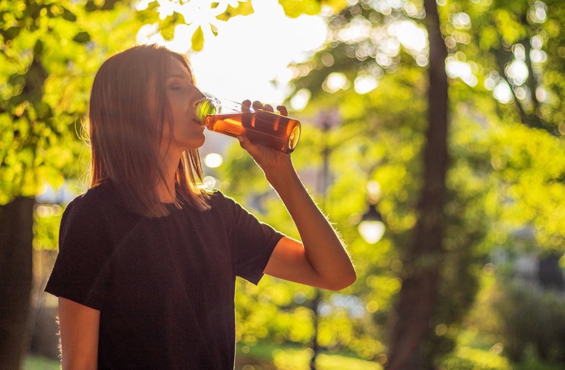 Chica en el parque bebiendo un té rojo con hielo